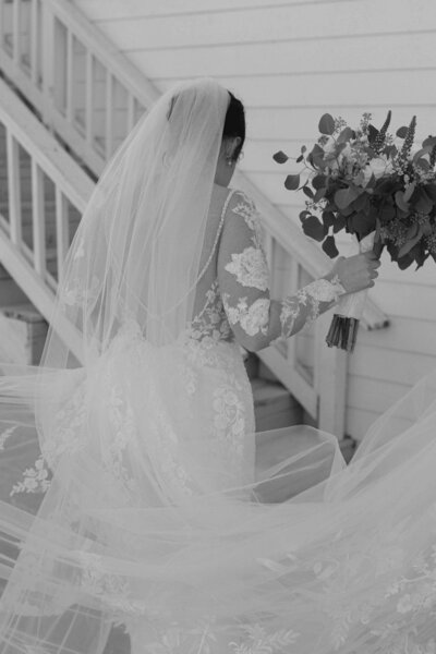 Bride with white lace dress and veil holding bouquet of flowers