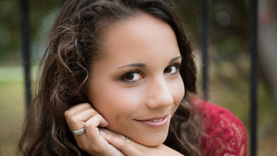 senior photo of girl looking at camera with hands on chin smiling