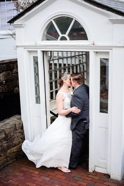 Couple sharing a kiss on their wedding day standing in a doorway at their venue in Boston