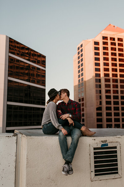 engaged couple kissing in front of a rainbow in albuquerque