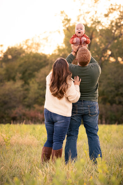 Siblings sitting on grass hugging  with fall leaves in background