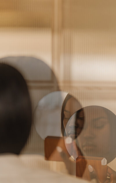 image of a woman looking in a mirror on a website for online therapy for moms of color