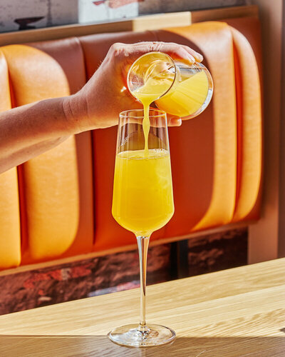 A refreshing mimosa  being poured into a champagne flute