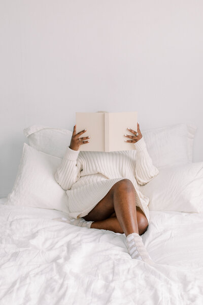 Image of black woman holding a book on a maternal wellness therapy website