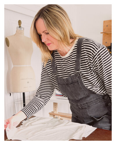 Doreen, freelance fashion designer, reviewing women’s apparel designs and fabric details in her studio during collection development.