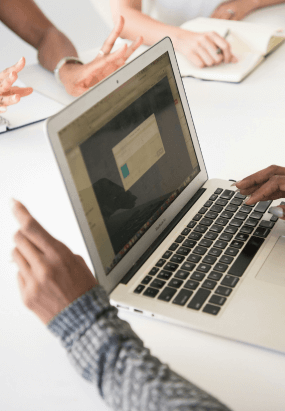 Close-up of hands on a laptop during a team meeting, symbolizing collaboration and strategic communication.