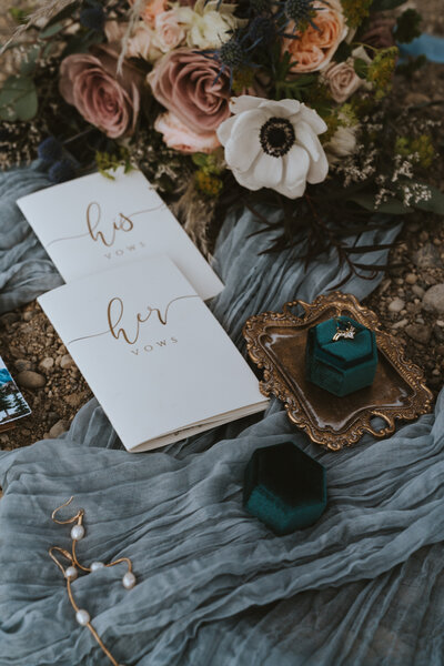 Flat layout of wedding details including vow books, ring, earrings and bouquet taken by California elopement photographer Kasey Mantiply