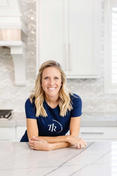 About our Frisco interior design services featuring a professional wearing a branded blue t-shirt with the submark logo, working in a kitchen design project.