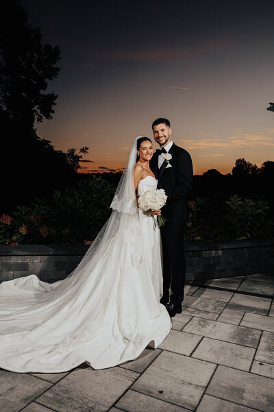 bride and groom posed outside at sunset