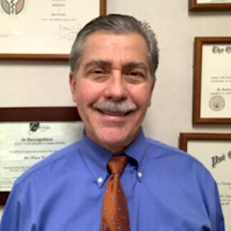 Dr. Tsivitse smiling in a blue shirt and red tie