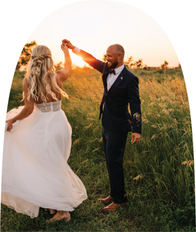 Groom twirling bride dancing at sunset