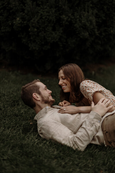 A playful engagement photoshoot capturing a couple rolling and laughing together in the grass. This candid moment highlights their genuine connection and joyful love, set against a natural outdoor backdrop—perfect for couples wanting fun, relaxed, and authentic engagement photography.

