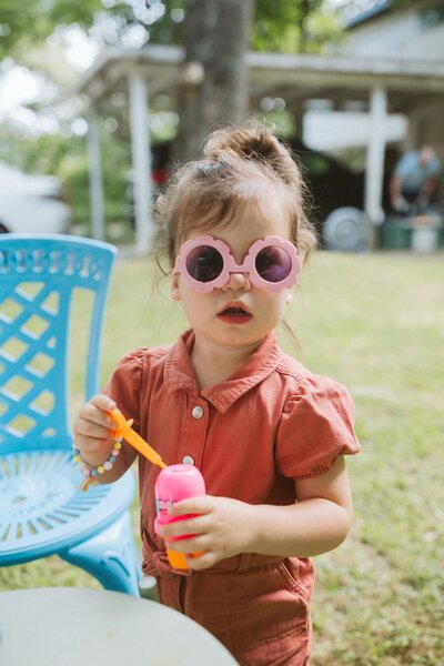 Girl kneeling down on floor with craft objects surrounding her for branding photography shoot in Austin, Texas