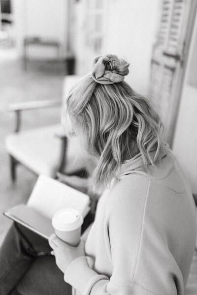 woman reading book with coffee in hand