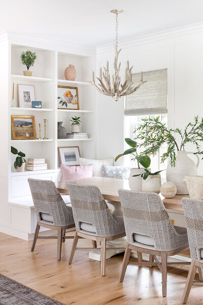 long dining table with chairs with white shelves in background 