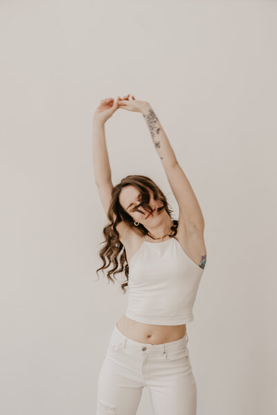 A UGC content creator in a white outfit and white background, dancing and having fun. 