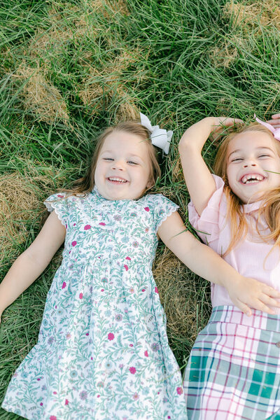 Rochester NY newborn photography and family photography session featuring two smiling girls laying in the grass.