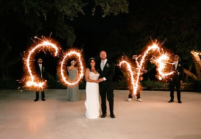 Couple at vow renewal with the word 'LOVE' spelled out in sparklers behind them in New Braunfels, TX.
