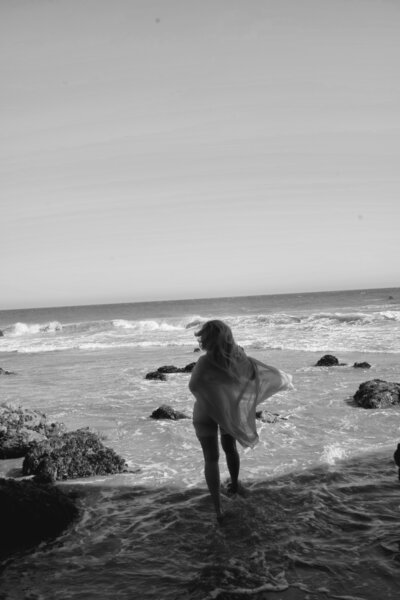 Nicky Lynn on the beach in a gold dress at sunset, embodying transformation and inner confidence