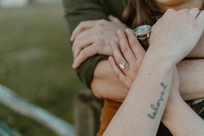 close up of engagement ring and people hugging