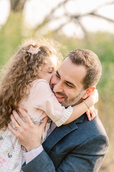 Young girl with curly hair hugging her Dad