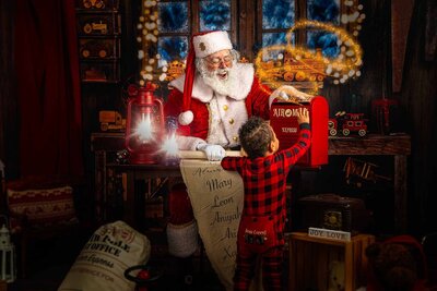 Santa with a little boy putting a letter in Santa's mailbox by Portrait Photographer in Austin