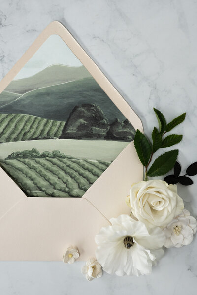 White wedding invitations with sage green envelopes and historic blue and white stamps