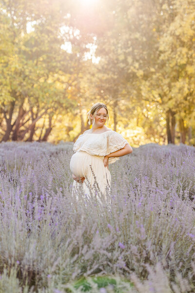Pregnant mother standing in a blue dress in golden light
