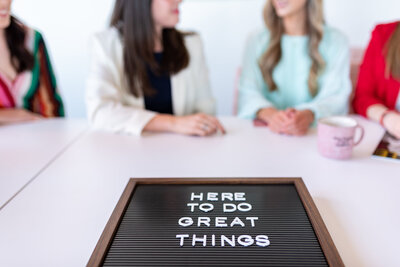 Two women seated at a table with a letterboard