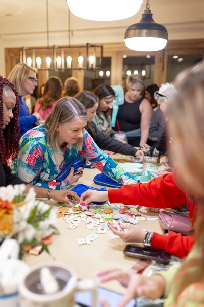 group of women standing around table working on crafts