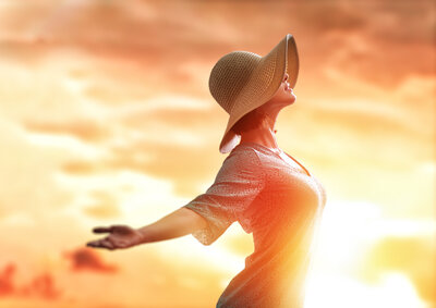 Woman facing the right side opening her arms to opportunity backlit by sun