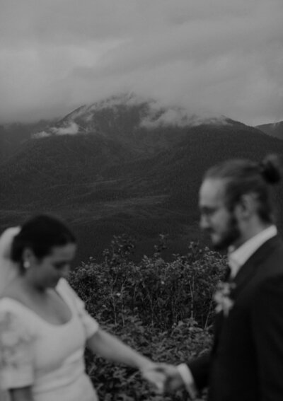 Couple holds hands with Alaska mountains behind them