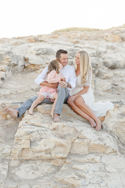 a family snuggling together on a rock at natural bridges state beach