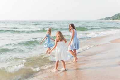 Mother and daughters playing in lake michigan water.