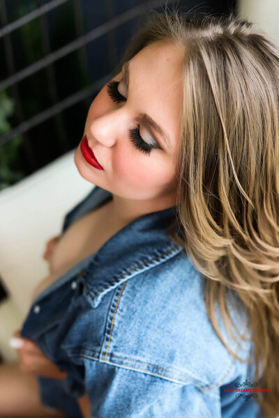 Woman sitting in a chair wearing a denim jacket with a red lip
