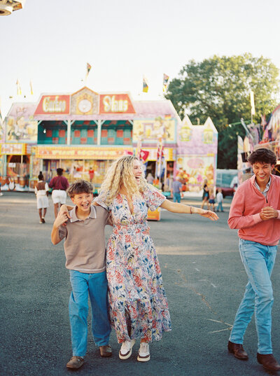 Blonde woman walking with two teenage sons while joyfully laughing at the Arkansas State Fair, capured on film by photographer Little Rock Bailey Feeler