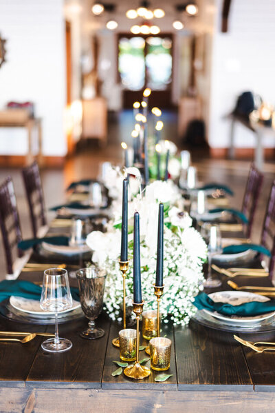 The indoor of the barn at Hidden Hill. A table is decorated for a wedding with candles, flowers, and glassware.