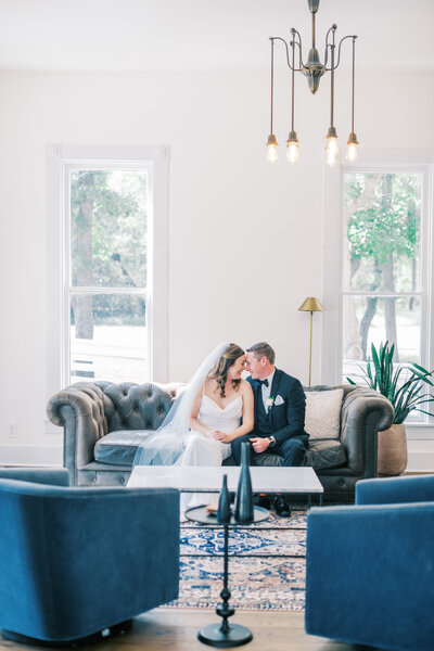 Bride and groom sitting together on a couch with their foreheads touching