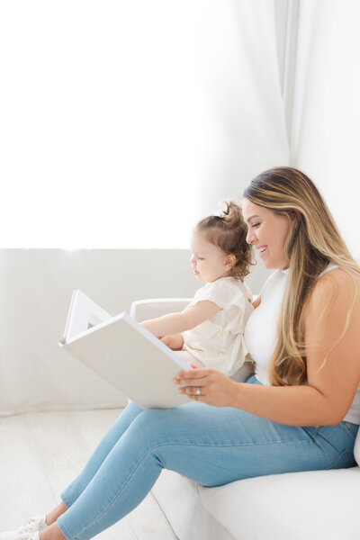 mom holding her toddler girl while flipping through the pages of her heirloom photo album