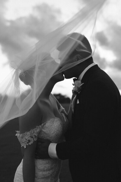 bride and groom kissing underneath bridal veil