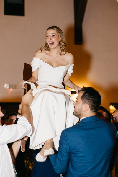 bride on chair during jewish wedding during the hora at viansa winery