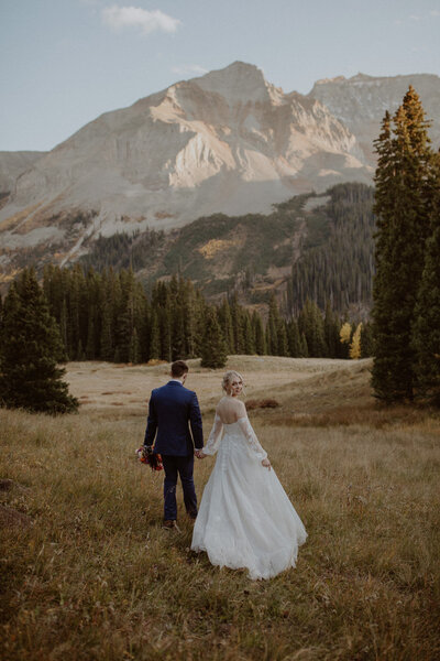 Bride and groom walk through the Telluride mountains