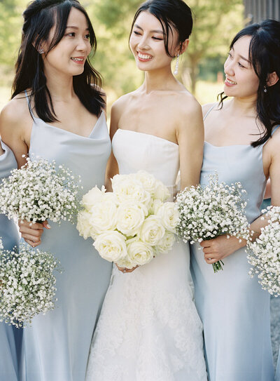 bridesmaids in blue satin dresses holding baby's breath floral bouquet's 