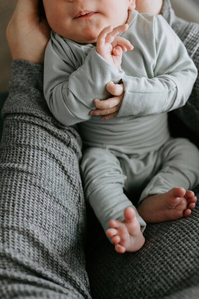 The newborn photo by Vanessa Stoller Photography focuses on a close up of the baby's hands and feet. 