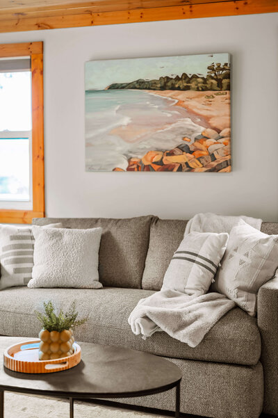 Gray couch with artwork depicting lakeshore