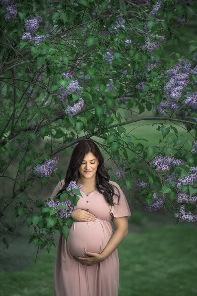 pregnant woman holds belly for maternity photos at Sayen Gardens in Hamilton, New Jersey.