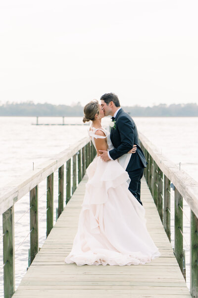 Lowndes Grove spring wedding pictures on the dock. Bride and groom kissing.