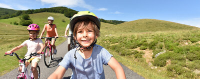MKP kid pictured biking on a paved mountain trail with his family