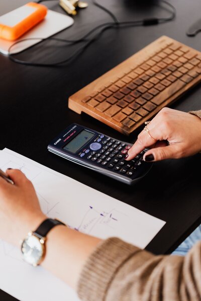 woman using a calculator and writing