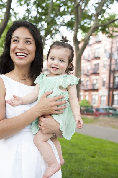 A parent holding a small child as they both smile 